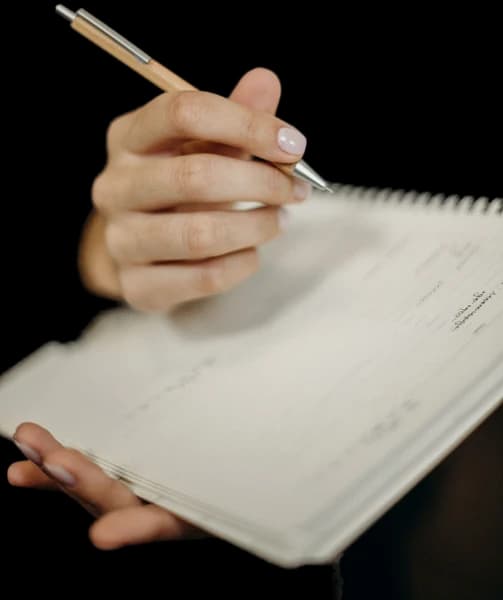 Hand holding fountain pen over open admission ledger book